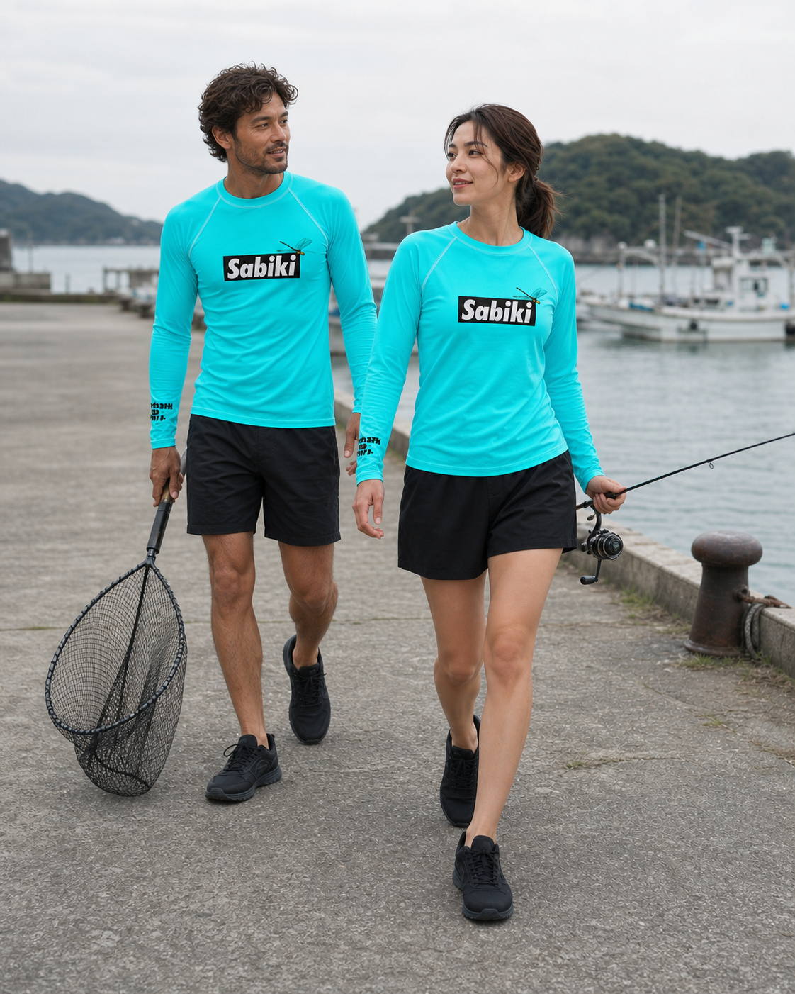 ターコイズのオニヤンマラッシュガードで、ロッドとネットを持って歩く女性と男性