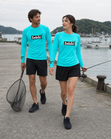オニヤンマ ラッシュガード｜ターコイズを港で着用する男性と女性