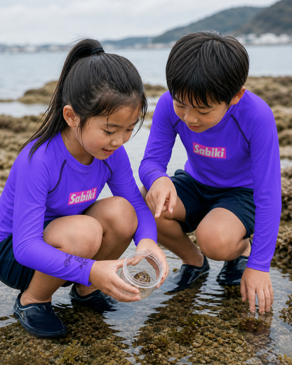 紫のSABIKI BOXキッズラッシュガードを着て潮だまりを観察する女の子と男の子