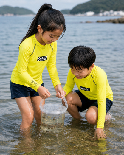 ネオンイエローのSABIKI BOXキッズラッシュガードを着て磯遊びをする女の子と男の子