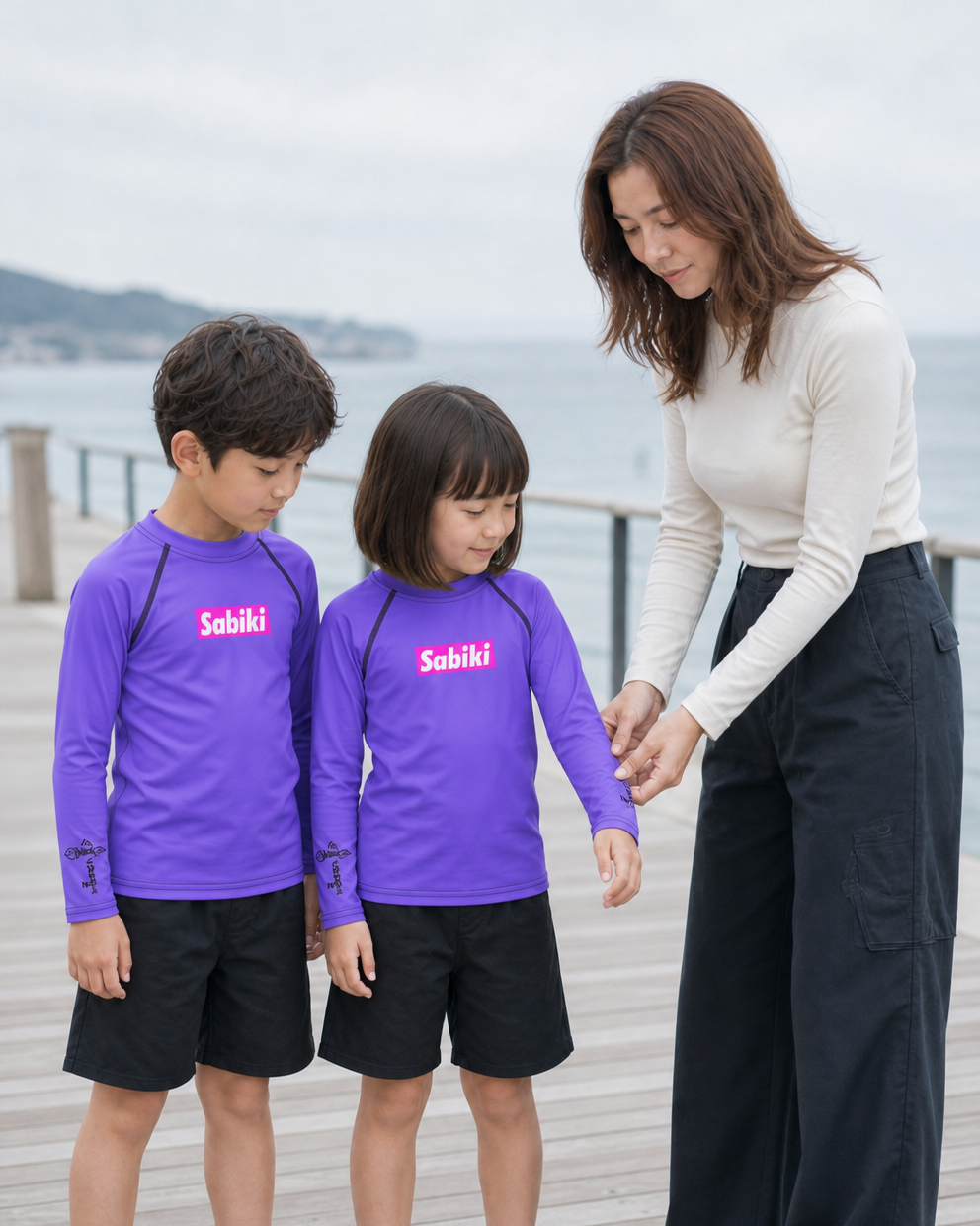 パープルのSABIKIラッシュガードを着用する女の子と男の子を見守る母親