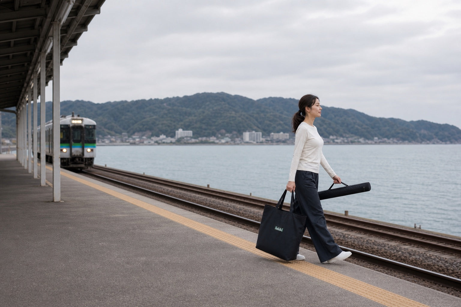 海辺の駅でSABIKIトートバッグを持って歩く女性